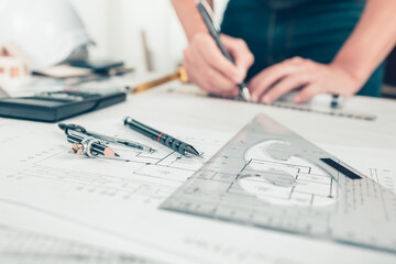 Architect engineer use pen, triangular angle ruler  and compass on drawing design working on...