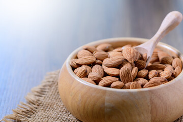 Almonds nut and wood spoon  in wood cup on wood background.