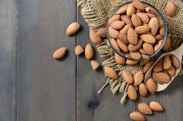 top view of Almonds in glass cup on wood background.