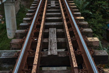 Obraz premium A railroad track made of iron, wood and gravel in a suburban area on a cloudy day in Indonesia