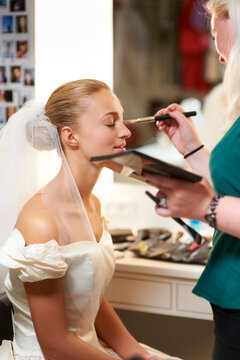 Making sure she looks perfect. A make-up artist applying make-up to a bride.