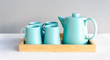 Teapot and cups, a set of dishes for tea drinking in a wooden tray.