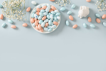 Easter frame with bunny, sweets as chocolate eggs, gypsophila on blue background. View from above....