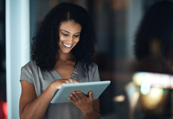 Connected around the clock. Shot of a young businesswoman using a digital tablet during a late...