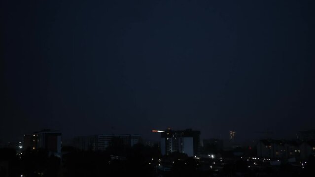 Thunderstorms, lightning over city. Flash strikes in stormy night falling on buildings in city. Lightning thunderstorm flashes over the night sky. Low key lighting. Underexposed. Blue light