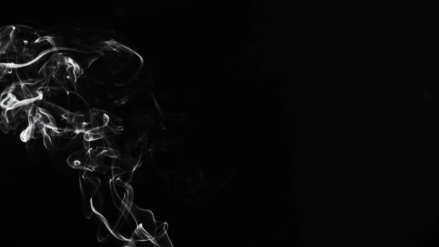 white smoke or dust, wavy and swirly on black background. perfect for compositing eg. hot tea, cigarettes or other smoking things