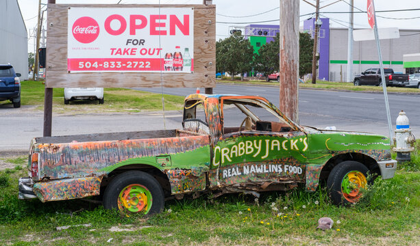 "Open" sign and painted beat up pickup truck that serves as corner sign for popular Crabby Jack's Restaurant in suburban New Orleans on March 3, 2022 in Jefferson, Louisiana, USA