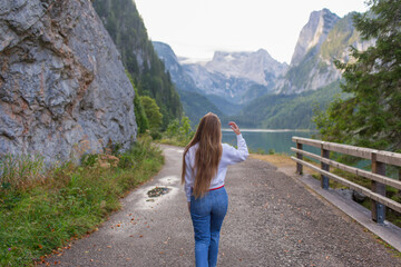 Fototapeta na wymiar Beautiful young girl walking by the lake in the Alps