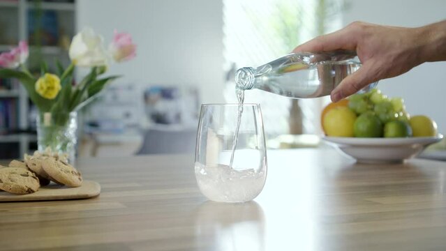 Pouring mineral water (sparkling water) in glass on table