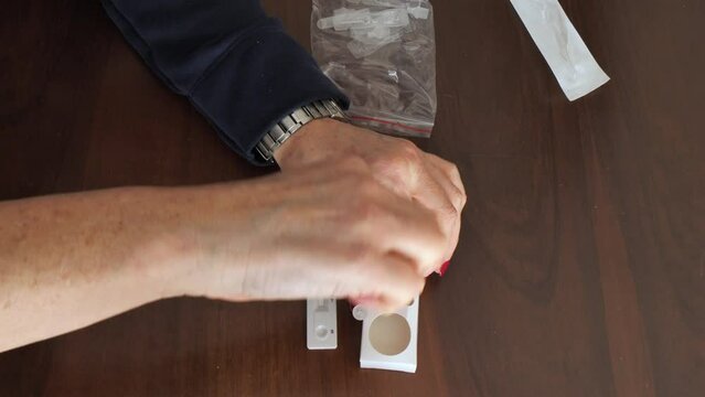 Caucasian woman female hand using a swab rapid home self kit test for detecting covid19 corona virus