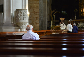 the elderly man prays in a church