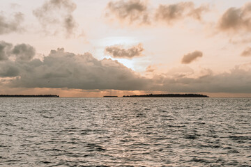 Naklejka na ściany i meble Sunrise in the ocean. Small Maldivian islands on the horizon.