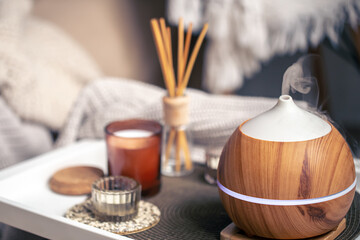 A cozy composition with an aroma diffuser and candles in a home interior.