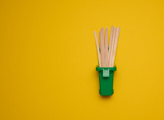 disposable wooden sticks for stirring hot drinks on a yellow background. Coffee and tea spoon