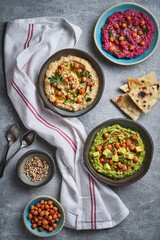 Various vegan hummus dips red beetroot green avocado and traditional chickpea.Traditional vegan hummus variety red beetroot green avocado and yellow chickpea with chia and sunflower seeds. Vegan diet 