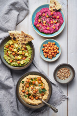 Various vegan hummus dips red beetroot green avocado and traditional chickpea.Traditional vegan hummus variety red beetroot green avocado and yellow chickpea with chia and sunflower seeds. Vegan diet 