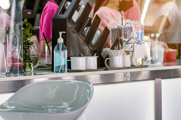 Blue alcohol gel bottle for hand cleaning to prevent the spreading of the Coronavirus (Covid-19) on counter to service for customers at cafe or coffee shop. Healthcare concept. New normal lifestyle.