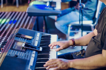 Musician play electronic keyboard synthesizers by using smartphone as guidelines for playing on the concert stage. Selective focus on smartphone.