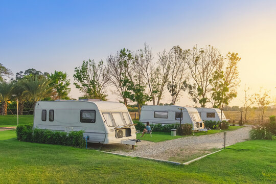 Cozy retro travel trailer Caravan on green grass before sunset near riverside in peaceful countryside. Family vacation travel RV, holiday trip in motorhome. Outdoor and Recreational Vehicles Theme.
