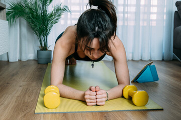 Young woman doing push-ups on yoga mat at home. Fitness girl doing pushups on exercise mat.