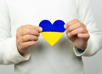 Girl holding a heart with the flag of Ukraine with both hands