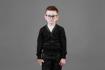 Portrait of a smart and serious child boy in glasses on a grey background close-up. Concept of school education, science and innovation, business development. copy space