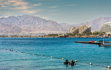 Divers prepare for underwater dive on coral reef near Eilat – famous tourist resort and...