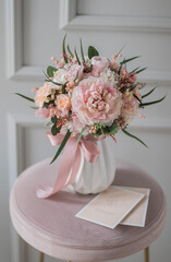 Bouquet with roses, hydrangea. Stabilized flowers in a white ceramic vase at home on the dressing table. Interior decor.