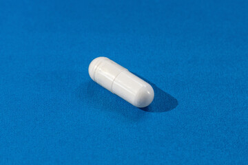 Ampoule tablets vitamin drug granules white powder in a soluble shell drink with water for body health close-up isolate on a blue background with copy space mockup
