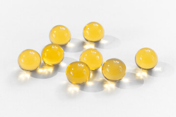 Yellow round capsules with fish oil for nutrition omega diet health benefits close-up on a white background with copy space