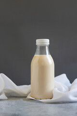 Bottle of potato milk placed on a neutral backdrop with a white cloth, showcasing a non-dairy alternative beverage.