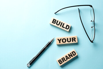Text BUILD YOUR BRAND concept on wooden block on the blue background