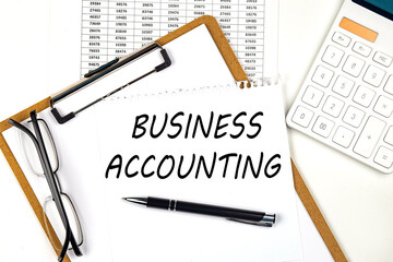 Text BUSINESS ACCOUNTING on the white paper on clipboard with chart and calculator