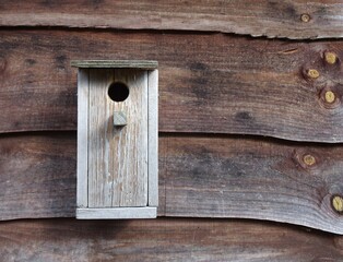 Wooden birdhouse against a wooden background.