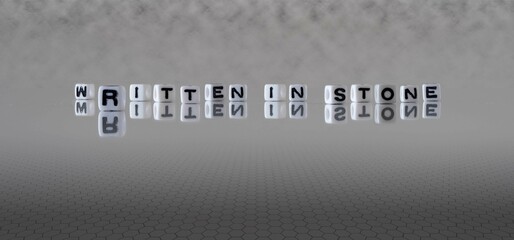 written in stone word or concept represented by black and white letter cubes on a grey horizon...