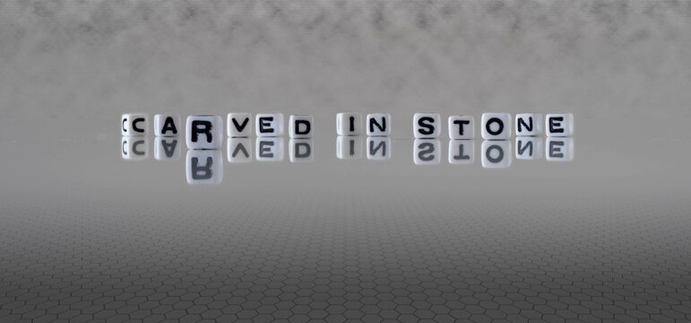 carved in stone word or concept represented by black and white letter cubes on a grey horizon background stretching to infinity