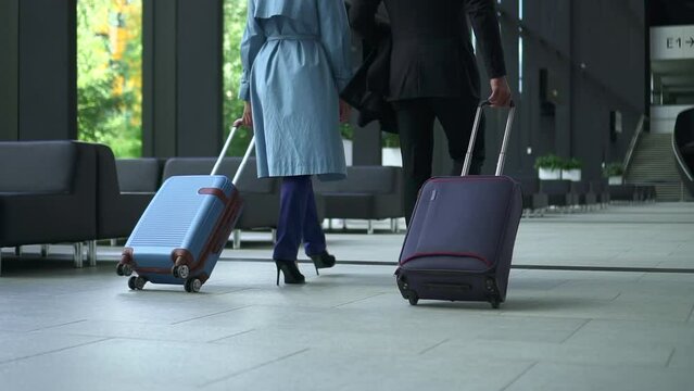 Back view of business people or couple holding suitcases and walking at airport indoors spbd. Shot of legs of young woman, man moves baggage and walks together, heads to check-in to fly away business