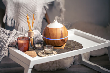 A cozy composition with an aroma diffuser and candles in a home interior.