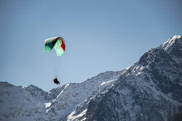 view of the silhouettes of two people paragliding with snowy mountains in the background in Loudenvielle, France