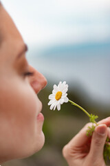 Close up photo of young woman smelling a daisy flower. Chamomile flower.