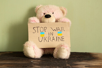 Stop the war in Ukraine is written on a sign that stands at home in Ukraine near a teddy bear....