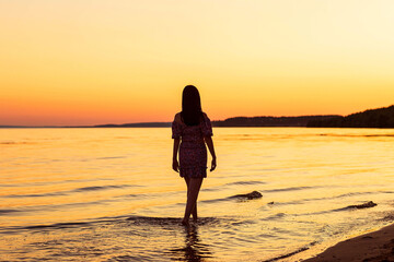 Fototapeta na wymiar a girl on the riverbank at sunset