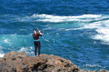 MUJER PESCANDO EN LA COSTA ROCOSA DE LA ISLA DE TENERIFE