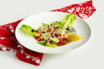 Fresh Healthy green salad in a dish isolated on colorful table cloth top view on grey background tomato, cucumber, onion, spinach, lettuce and sesame