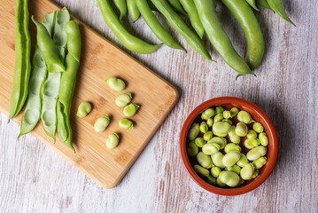 Broad beans on a white wooden table, top view.