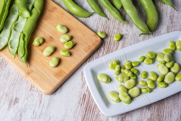 Broad beans on a white wooden table, top view.