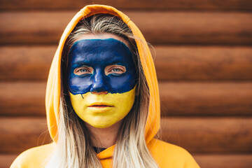 Outdoor portrait of young girl with blue and yellow ukrainian flag on her cheek