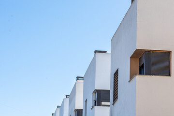 Perspective of several white modern houses in a row with the blue sky in the background