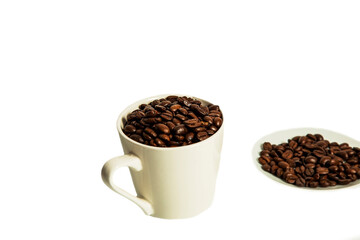 Coffee beans lie in a white mug and saucer on a white background. Isolate.