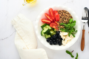 Healthy vegetable lunch from the Buddha bowl with with tomato, cucumber, mozzarella cheese, quinoa, olives and microgreens. Vegan salad buddha bowl. Healthy and balanced food concept.